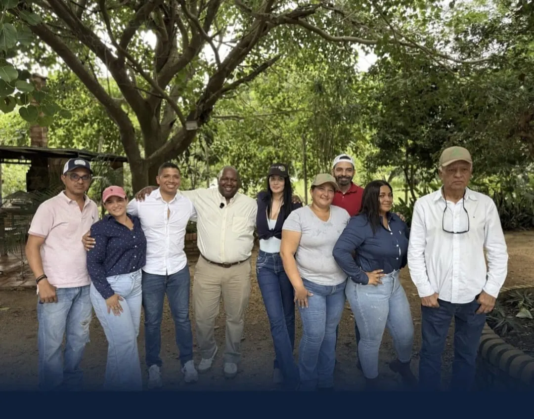 Members of the visiting delegation and local producers pose together beneath trees.